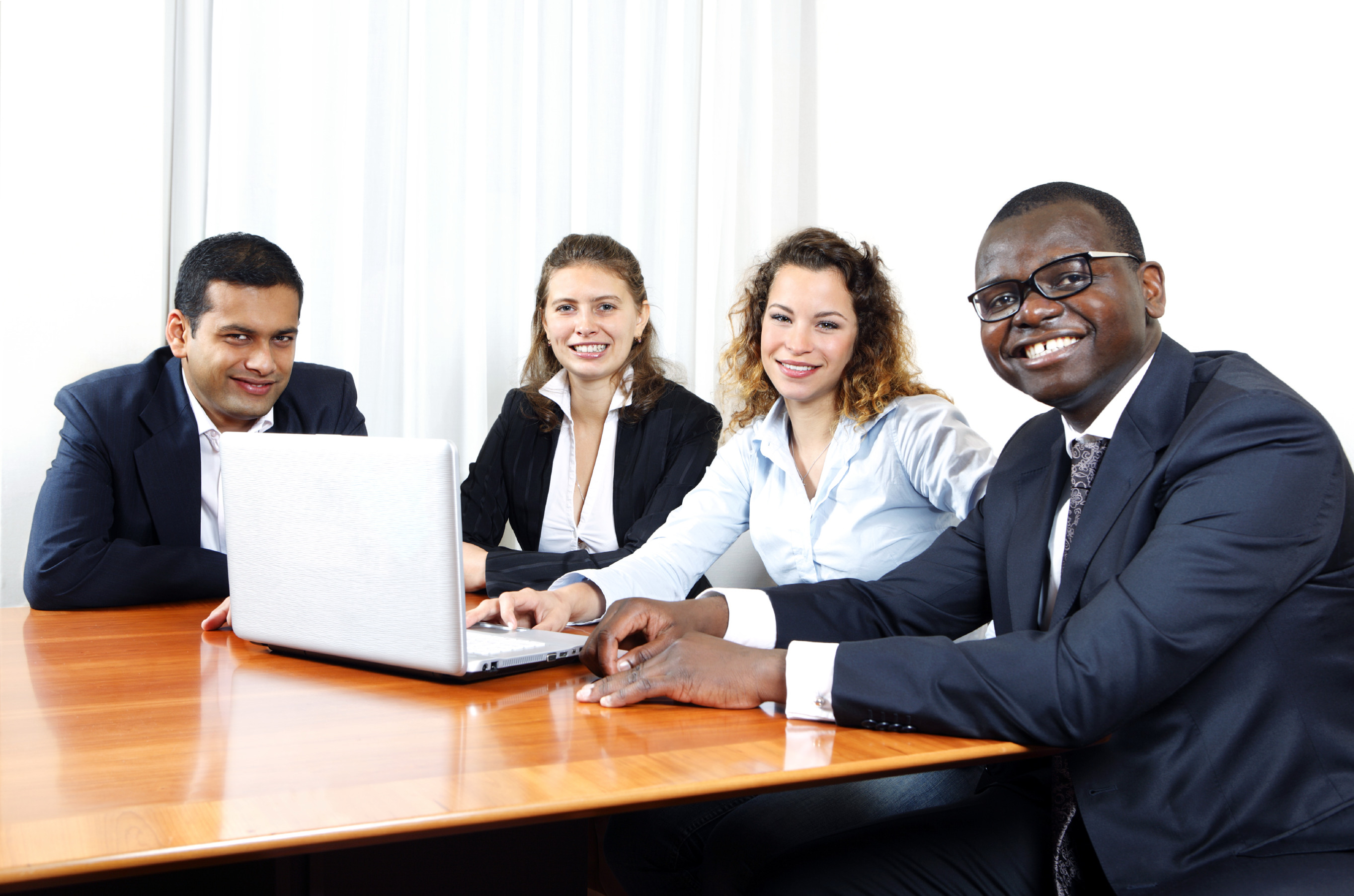 A diverse team of young business people looking at a laptop computer and discussing a project.